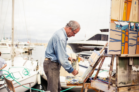 SAINT TROPEZ, FRANCE - OCTOBER 18, 2013: Street artist in Saint Tropez painting and selling his work along the harbour on October 18, 2013, Saint Tropez, Franceのeditorial素材
