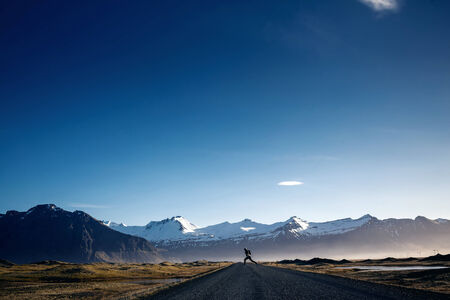 Man jumping on Winding mountain roadの写真素材
