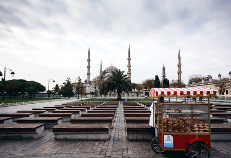 ISTANBUL, TURKEY - NOVEMBER 28: Salesman of baked bagels with little truck in front of Famous Sultan Ahmed Mosque (Blue Mosque) in Istanbul, Turkey on November 28, 2014のeditorial素材