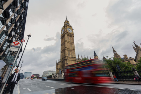 LONDON, UK - AUGUST 24, 2015: Double-decker bus passes pedestrians walking in front of Big Ben and Houses of Parliament on Westminster Bridge.のeditorial素材