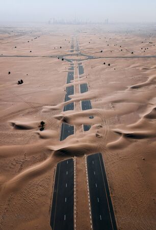 Empty road in desert covered by sand, Dubai, UAE