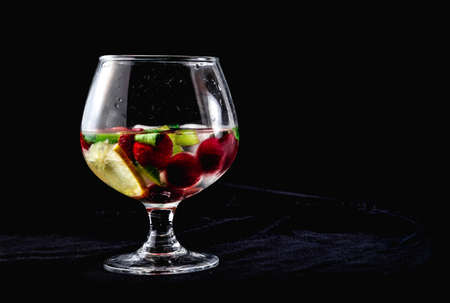One cocktail with ice lemon mint strawberries sweet kiwi in cognac glass on a black background oneの写真素材