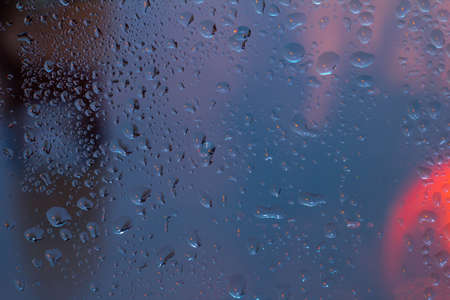 Raindrops on the surface of window panes Natural pattern of raindrops, on a blue background.の写真素材
