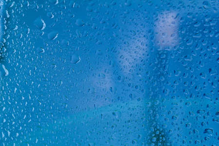 Raindrops on the surface of window panes Natural pattern of raindrops, on a blue background.の写真素材