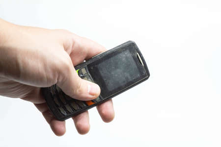 Old shabby phone in hand on a white background isolateの写真素材