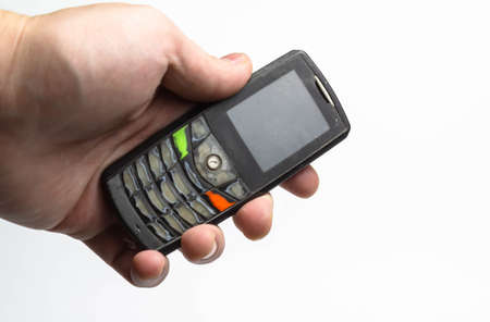 Old shabby phone in hand on a white background isolate