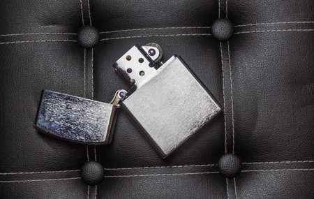 Chrome gasoline lighter on black leather with seams