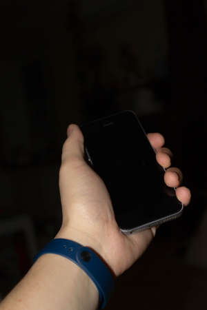 Phone in hand with a bracelet on a dark background