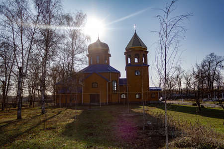 Wooden church with birches on a background of sunny sunsetの写真素材
