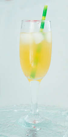 champagne glass with cocktail, juice with ice green straw on water light backgroundの写真素材