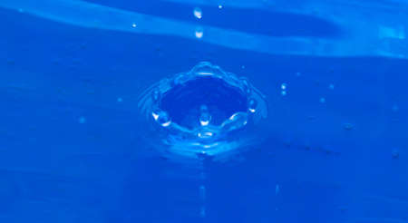 a drop falls into blue waterの写真素材