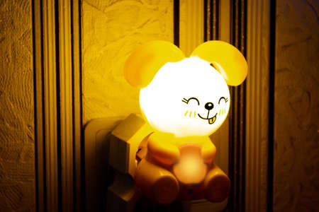 a bunny-shaped night light shines yellow in the socketの写真素材
