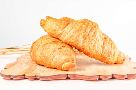croissants with dry wheat on a wooden board on a white backgroundの写真素材