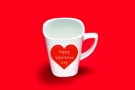White square cup with a heart and the inscription "Happy Valentine's Day" on a red background. copy spaceの写真素材