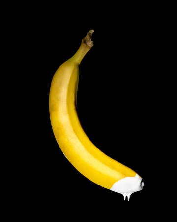 banana with white icing on the end. sex, food porn, sexually on a black background isolate. copy spaceの写真素材