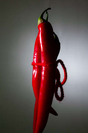 Red hot peppers are connected by a red thread. sex, sexually on a black background. copy spaceの写真素材