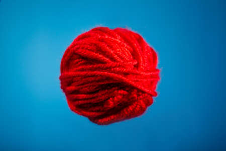 red skein of knitted thread. copy space. on a blue backgroundの写真素材