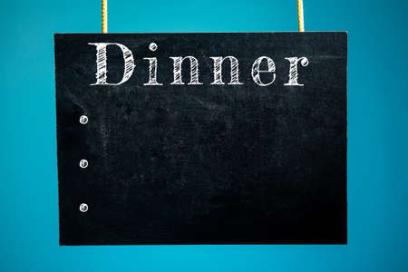 Chalk board hanging with the words "dinner" and dots mocap on a blue background. copy spaceの写真素材
