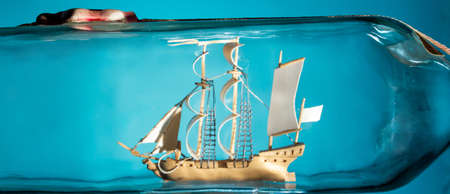 ship in a glass bottle at an angle on a blue background. copy spaceの写真素材