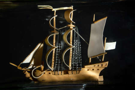 ship in a glass bottle at an angle on a black background. close up, copy space