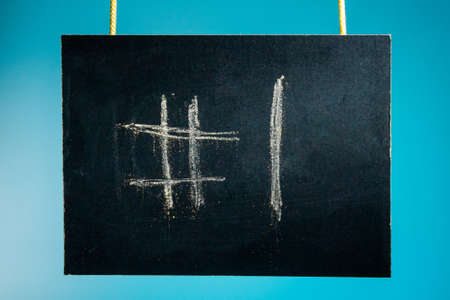 Chalk board is hanging with the inscription "# 1" on a blue background. copy spaceの写真素材