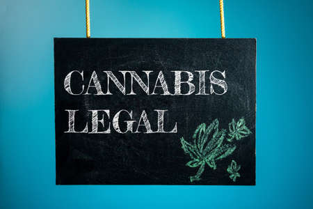 A chalk board is hung with the words "cannabis legal" and a pattern of cannabis on a blue background. copy spaceの写真素材