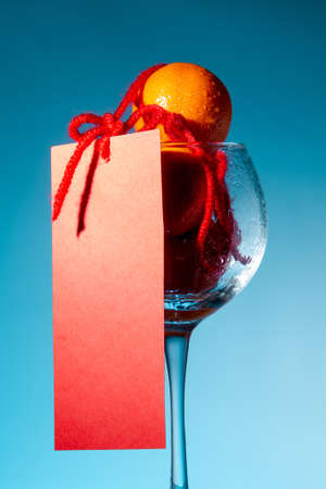 tangerines in a glass goblet and red piece of paper chinese new year mocap on blue background, close up, copy spaceの写真素材