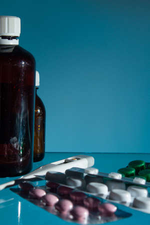 medical jars, thermometer, syringe, gauze mask and pills medicines, medicine on glass blue...