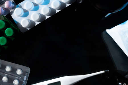 medical jars, thermometer, syringe, gauze mask and pills medicines, medicine on glass black background close up. copy spaceの写真素材