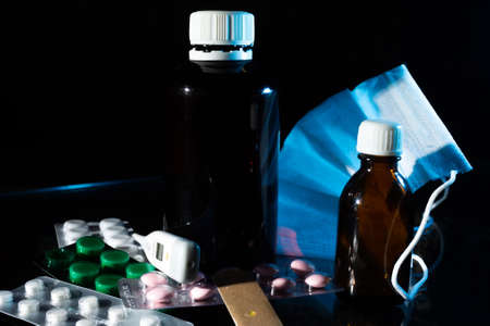 medical jars, thermometer, syringe, gauze mask and pills medicines, medicine on glass black...
