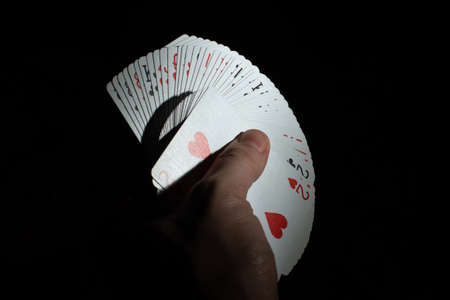 hand hold a fan from a deck of poker cards on a black background copy space. close up