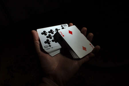 hand hold a deck of cards one hand shuffle volt poker on a black background copy space. close upの写真素材