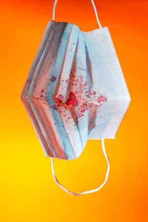 Medical gauze mask in dried blood on an orange background. close up copy spaceの写真素材