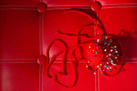 a red skein of thread stuck a lot of needles on red leather. close up copy spaceの写真素材
