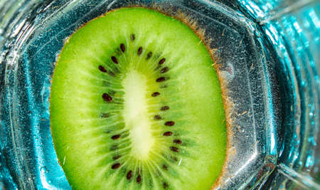 green kiwi with pits with bubbles in glasses on ice on a blue background. close upの写真素材