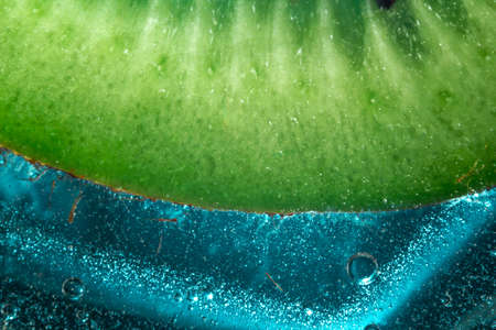 green kiwi with pits with bubbles in glasses on ice on a blue background. close upの写真素材