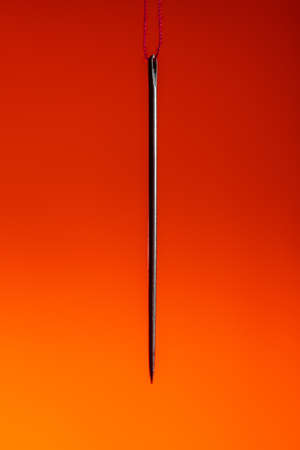 a needle hanging on a red thread on a Lush Lava background. close up copy spaceの写真素材