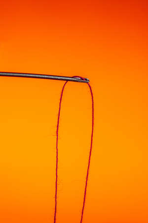 a needle hanging on a red thread on a Lush Lava background. close up copy spaceの写真素材