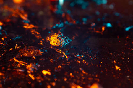 coals scatter in different directions with a blue-orange backlight on a dark background. close up copy spaceの写真素材