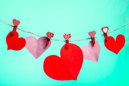 Paper hearts of red clothespins with a heart on a rope. Valentine's Day love. Background Aqua Menthe. copy spaceの写真素材