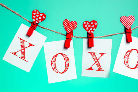 pieces of paper with the words "xoxo" red clothespins with a heart on a rope. Valentine's Day love. Aqua Menthe Background. copy space. mocapの写真素材