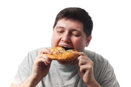 Young guy in gray pretty eating baked bread product on white background copy spaceの写真素材