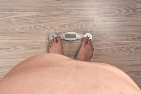 fat man on glass scales with a belly wooden parquet background