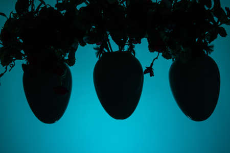 Three hanging pots with artificial flowers. Decorative element of the house on a blue background. Copy space.の写真素材