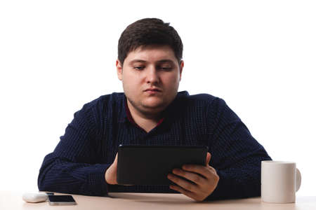 Young guy in a blue shirt looks at the tablet, office worker, business. on white background. isolate. copy spaceの写真素材