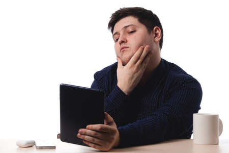 Young guy in a blue shirt use a tablet as a mirror office worker, business. on white background. isolate. copy spaceの写真素材
