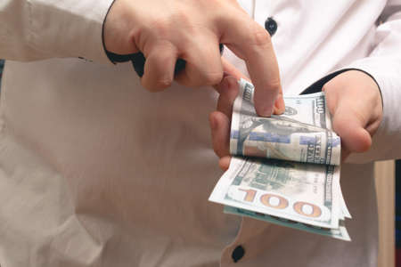 Caucasian man counts money hundred dollar bills in a white shirt in the officeの写真素材