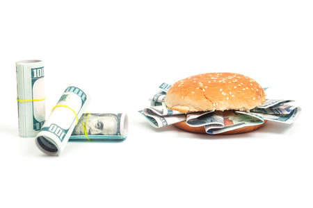 burger with hundred dollar bills instead of toppings and rolls of hundred dollar bills on a white...