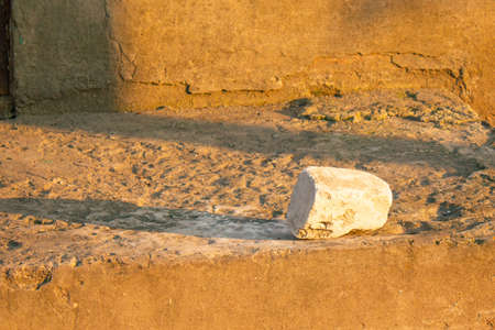white brick fragment under the setting sun on concrete with a long shadow copy space