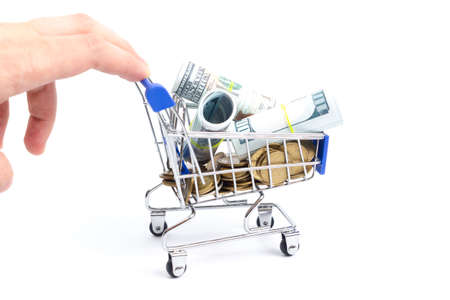 shopping cart with coins and rolls of dollars pushed by hand on a white background.の写真素材